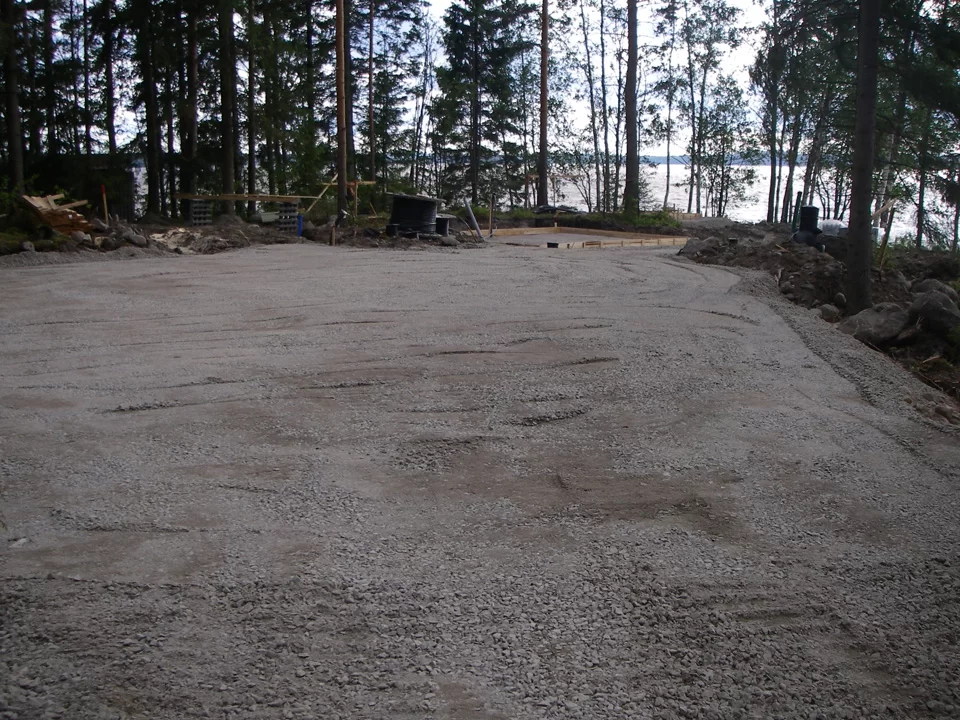 Tasoitettu sorapinta hirsimökin tontilla valmiina toimituksen vastaanottoa varten.