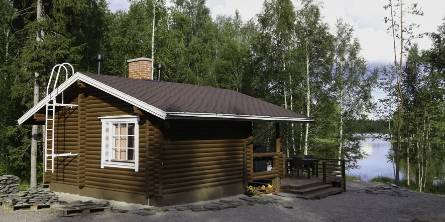 Tumma 20 neliömetrin kokoinen saunamökki järvellepäin suunnattuna