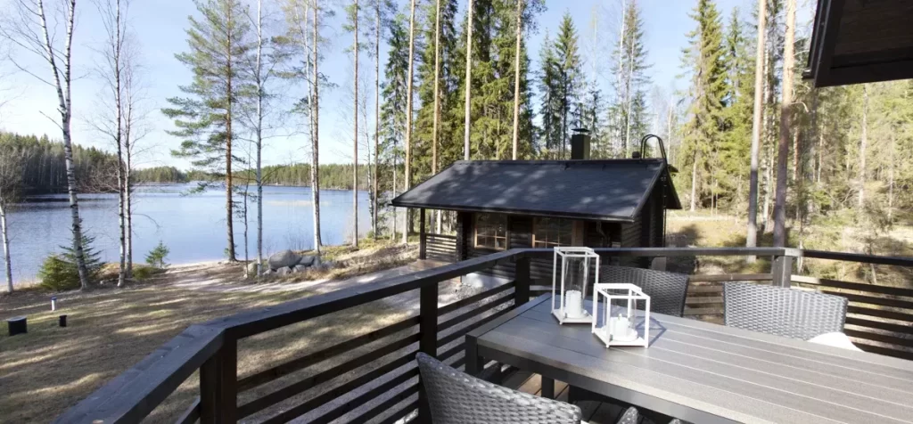 Tumma rantasauna terasilla järven rannalla